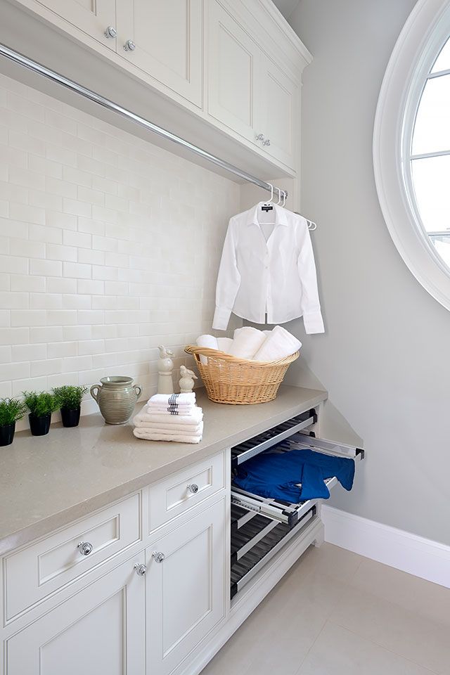 a kitchen with white cabinets and an open drawer in front of a round window that has potted plants on it