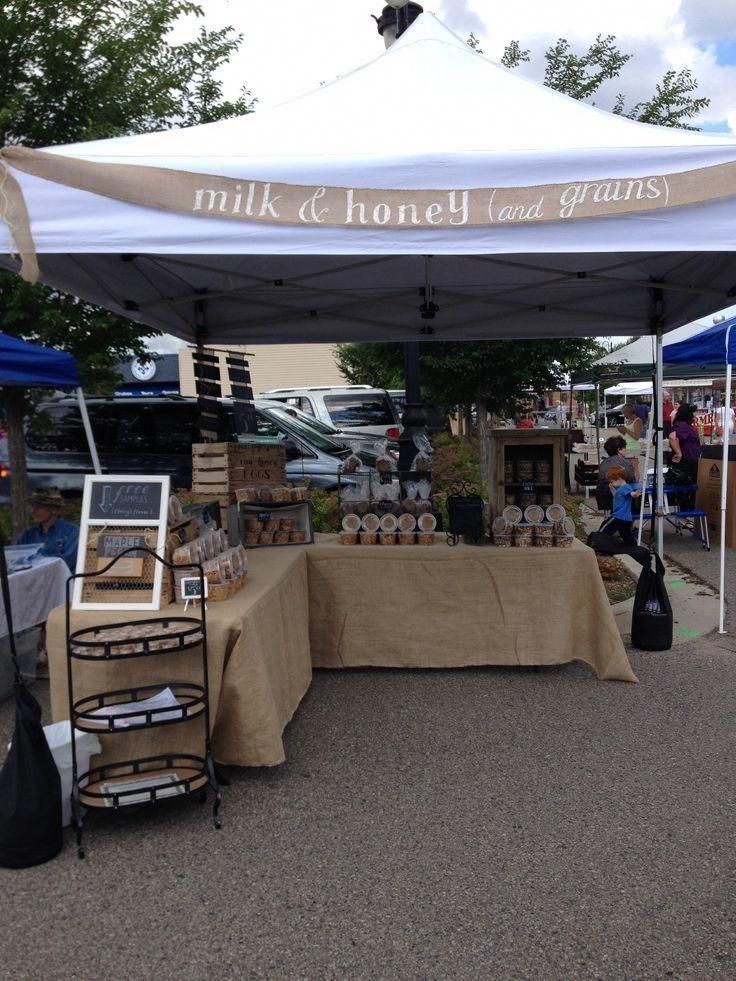 an outdoor market with tables and umbrellas on the side walk, selling items for sale