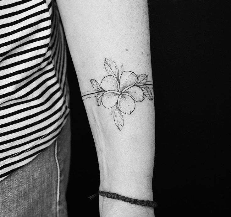 a black and white photo of a woman's arm with a flower tattoo on it