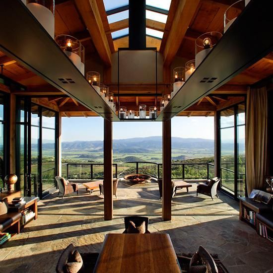 an open living room with lots of furniture and windows overlooking the mountains in the distance