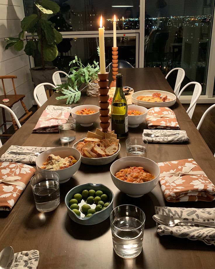 the table is set with many different foods and drinks, along with a lit candle