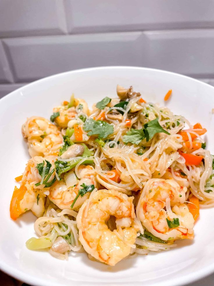 a white plate topped with pasta and shrimp