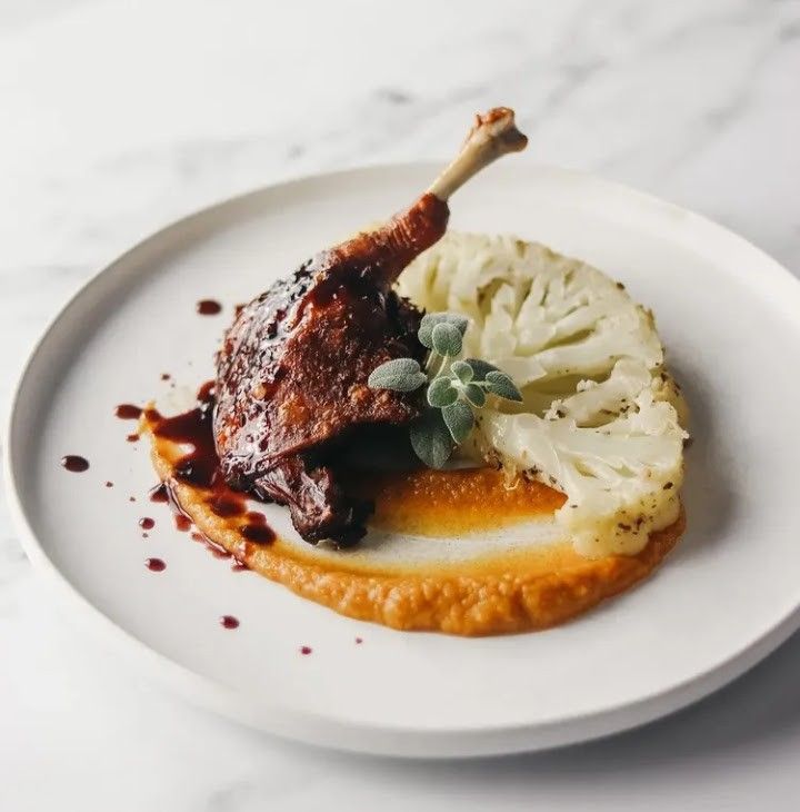 a white plate topped with meat and mashed potatoes on top of a marble table