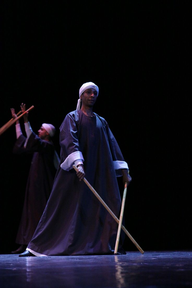 two men dressed in robes and holding crucifixs are standing on stage