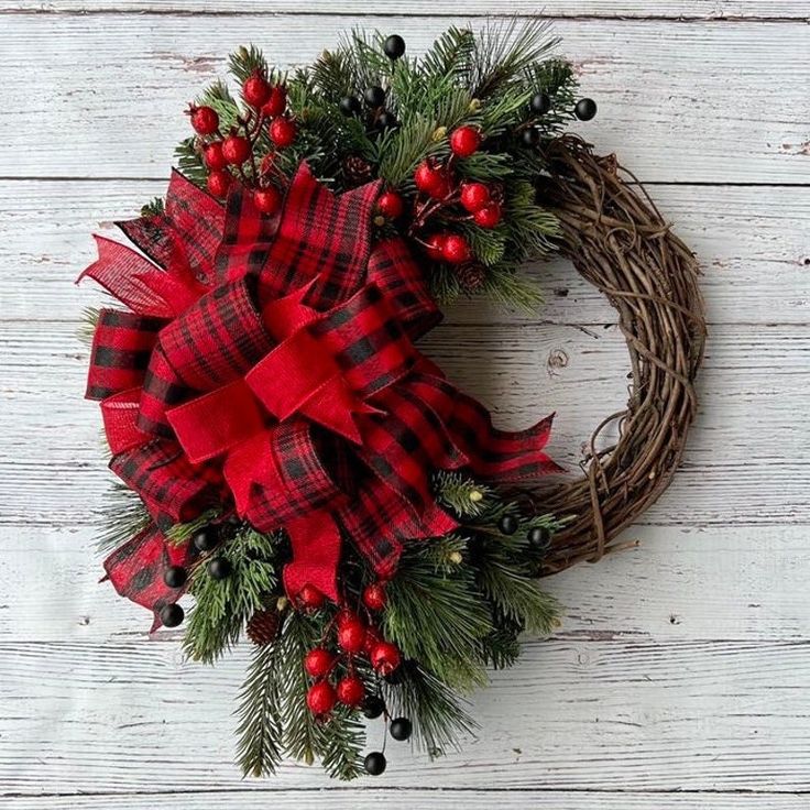 a wreath with red and black plaid bows on it sitting on top of a wooden table