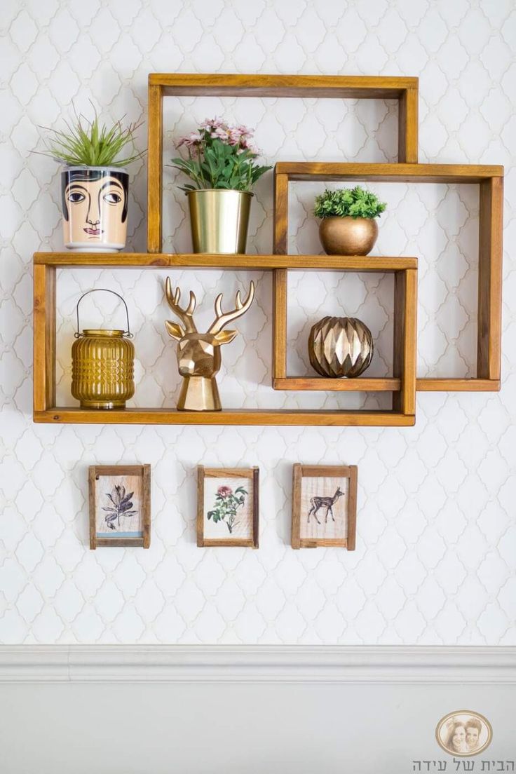 three wooden shelves with plants and pictures on the wall next to each other in front of a white wall