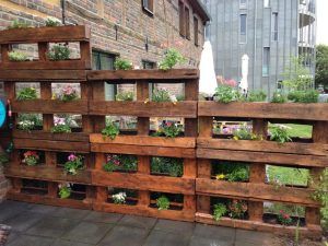 several wooden pallets with plants growing in them on the side of a brick building