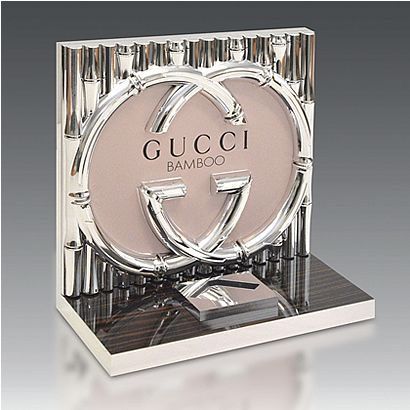 a gucci bamboo perfume bottle sitting on top of a glass block with the words gucci in it