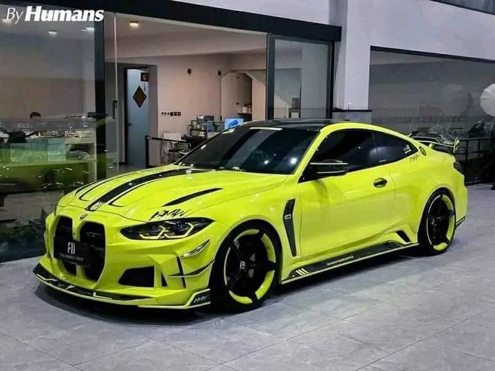 a bright yellow sports car parked in front of a building with black stripes on it