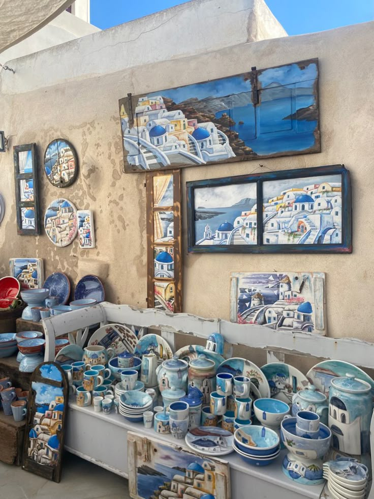 an outdoor market with pottery and pictures on the wall