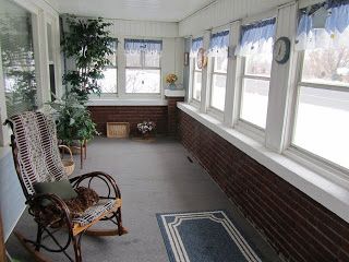 an empty porch with rocking chairs and potted plants on the windows sills