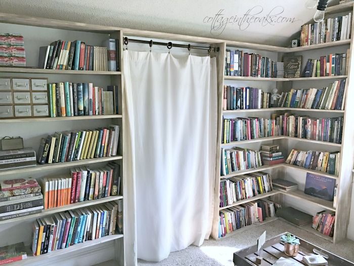 a living room filled with lots of books on top of book shelves next to a window