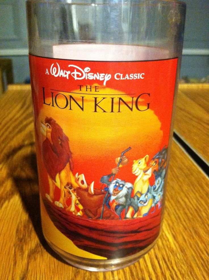 the lion king candle is sitting on a wooden table next to a glass with an image of simba and simba