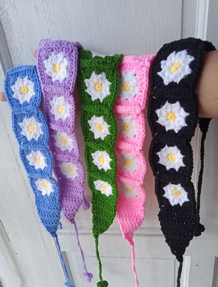 four crocheted headbands hanging from a door