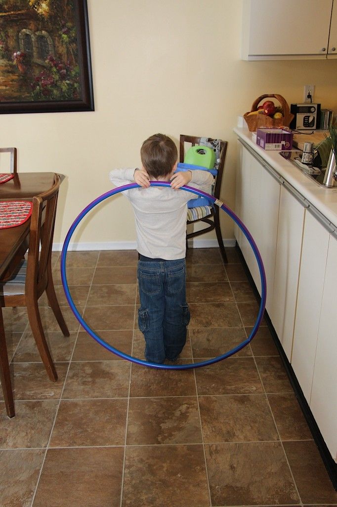 a young boy is playing with a blue hula hoop in the middle of a kitchen