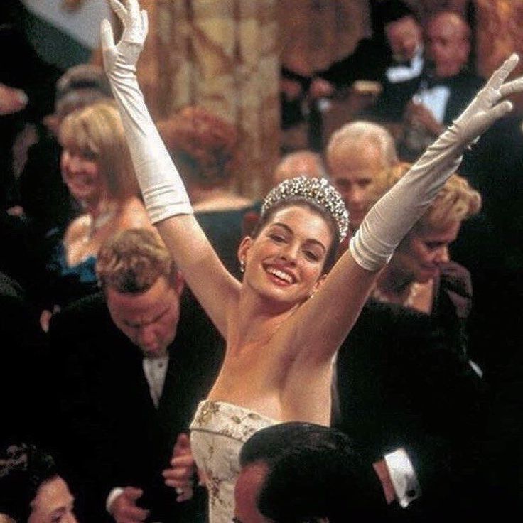 a woman wearing a tiara and holding her arms up in the air at an event