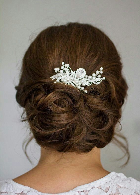 a woman wearing a wedding hair comb with pearls on it's head and her hair in a low bun