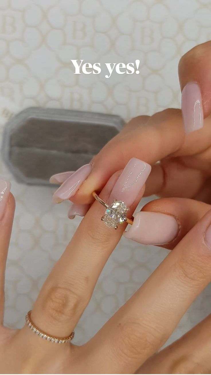 two hands with pink and white manies on their nails, one holding a diamond ring