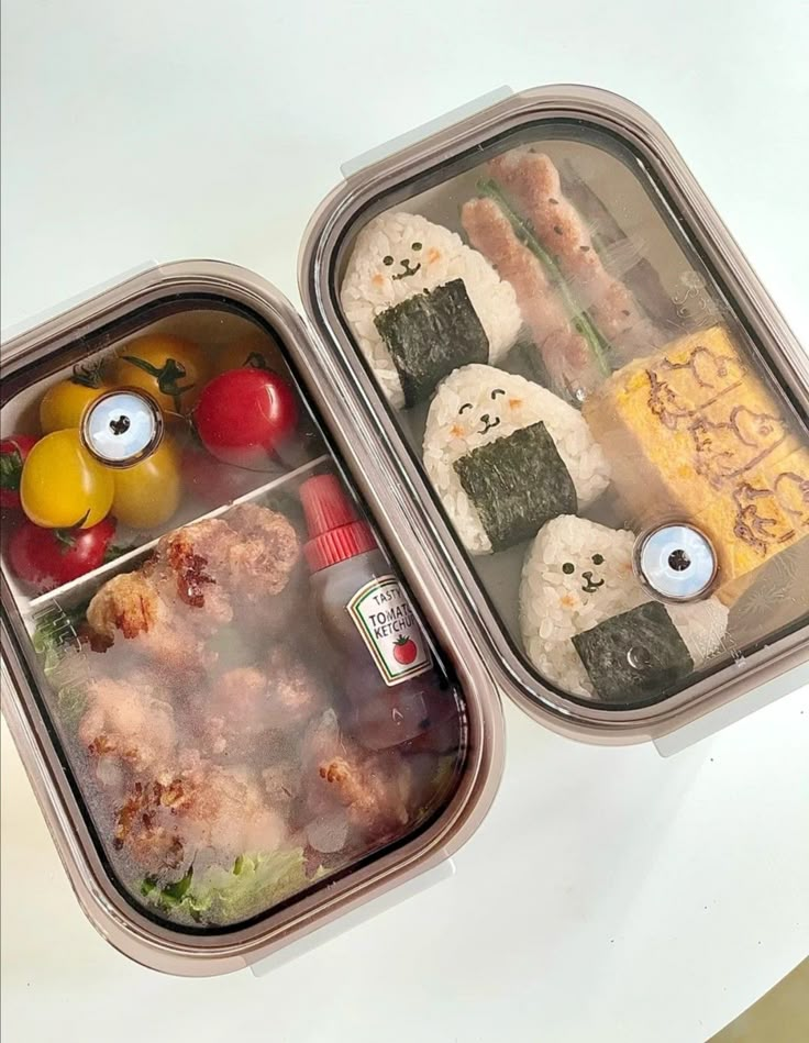 two bento boxes filled with food on top of a white table next to each other