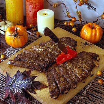 a wooden cutting board topped with meat next to candles and pumpkins