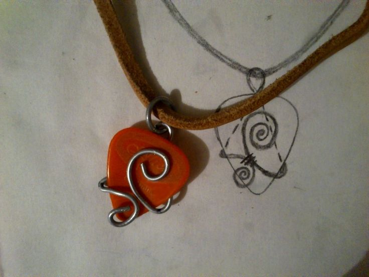 an orange heart shaped pendant is on a brown cord with a wire wrapped around it