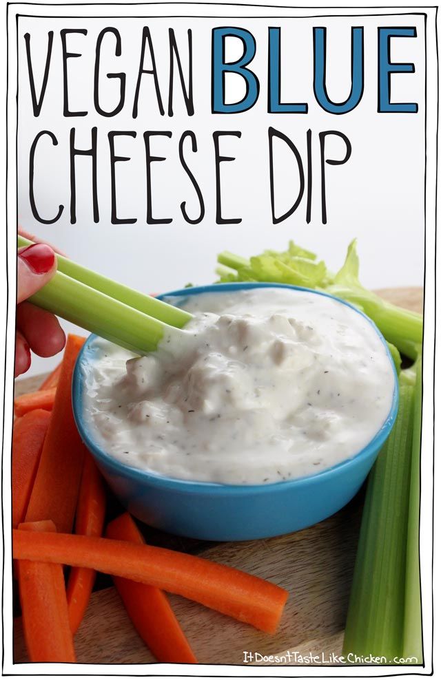 a blue bowl filled with dip surrounded by carrots and celery