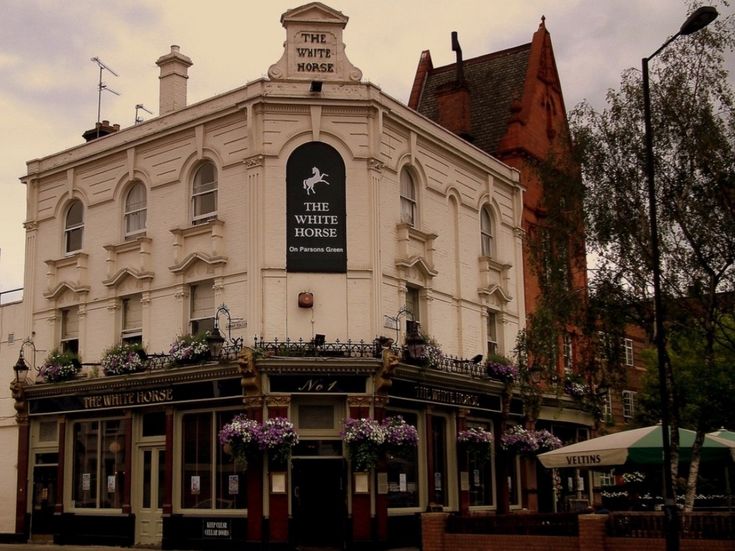 the white horse pub in an old european town with flowers growing on it's roof