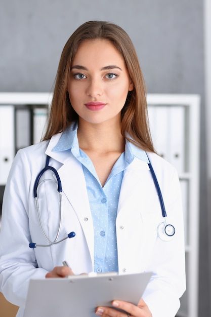 a female doctor is holding a clipboard in her hand and looking at the camera