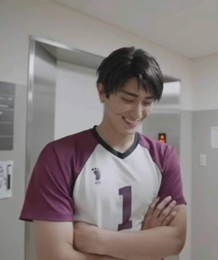 a young man is smiling and looking at his hands on his chest while standing in front of an elevator