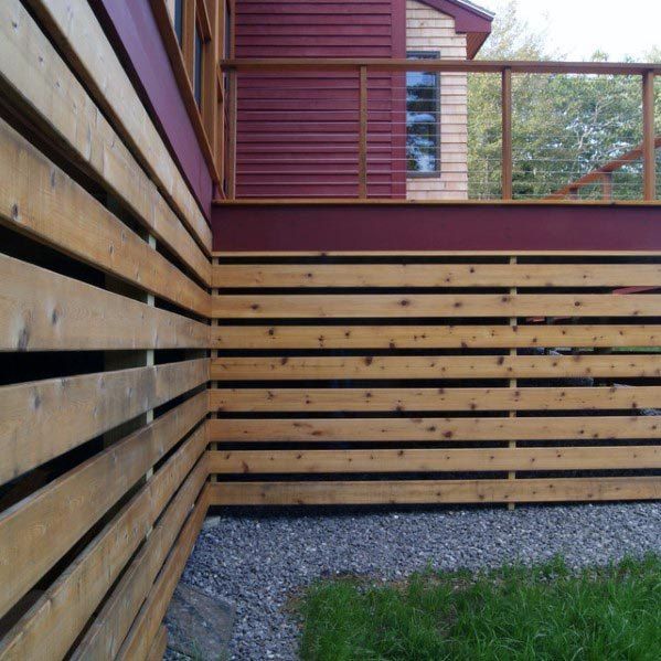 a wooden fence next to a house with red siding and wood slats on it