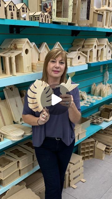 a woman standing in front of shelves filled with birdhouses and other wooden buildings on display