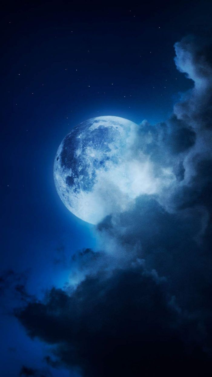 the full moon is shining brightly in the night sky with clouds and dark blue hues