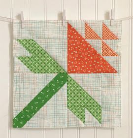 an orange and green quilt hanging on a wall