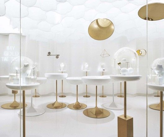 a room filled with lots of white tables and gold pedestals on top of each other