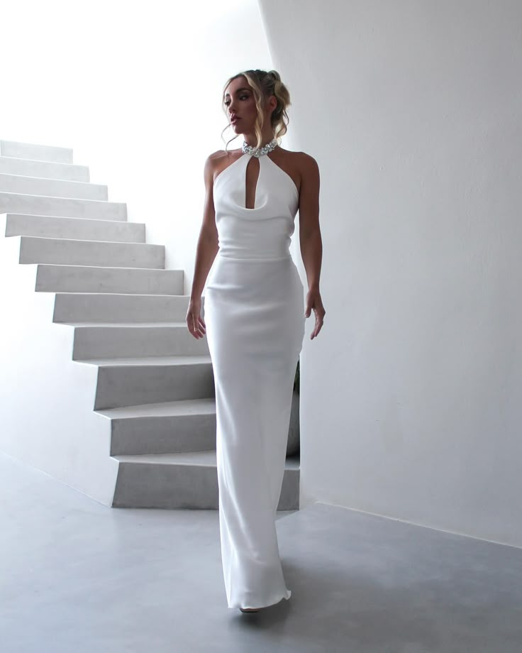 a woman in a white dress standing next to some stairs