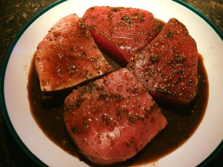 three pieces of meat on a plate covered in gravy and pepper sprinkled