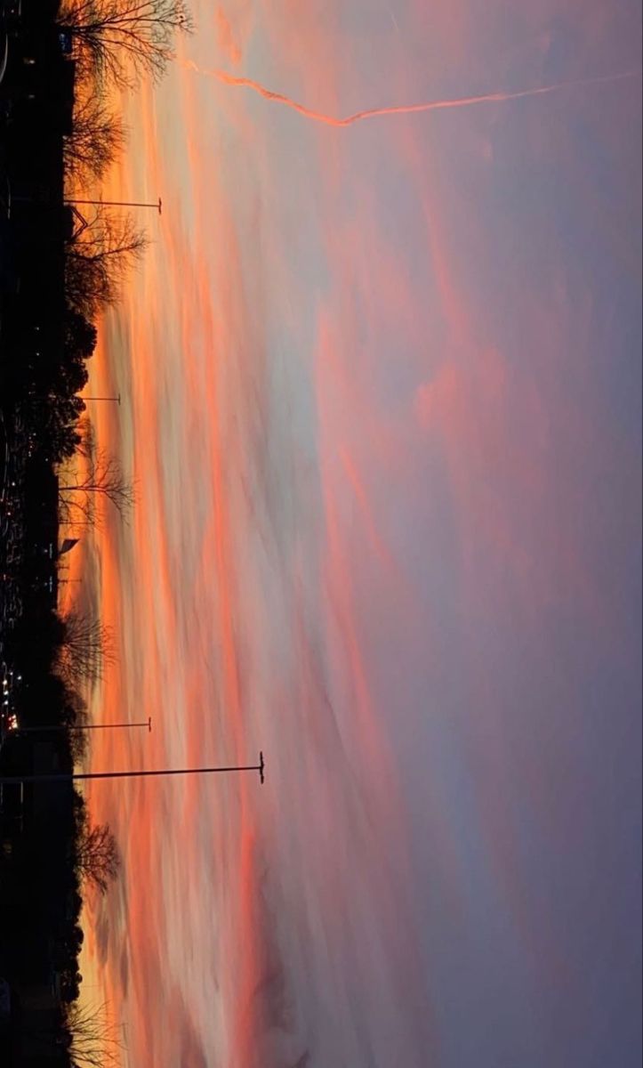 an orange and pink sky is reflected in the water