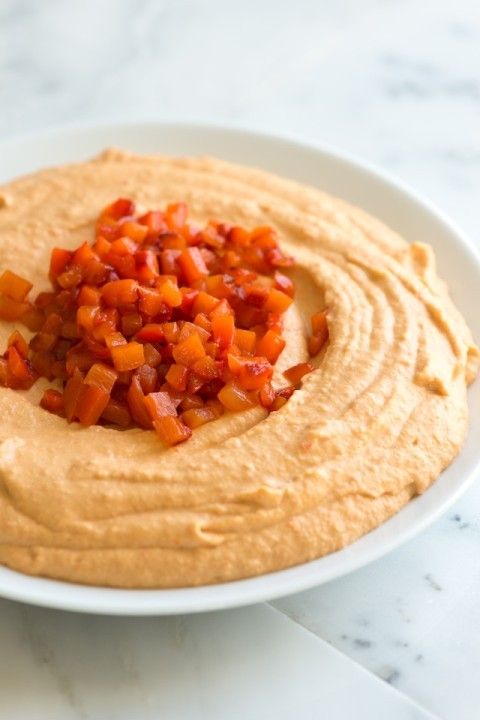 a white plate topped with hummus and chopped carrots