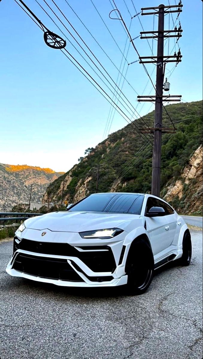 a white sports car parked on the side of a road with power lines in the background