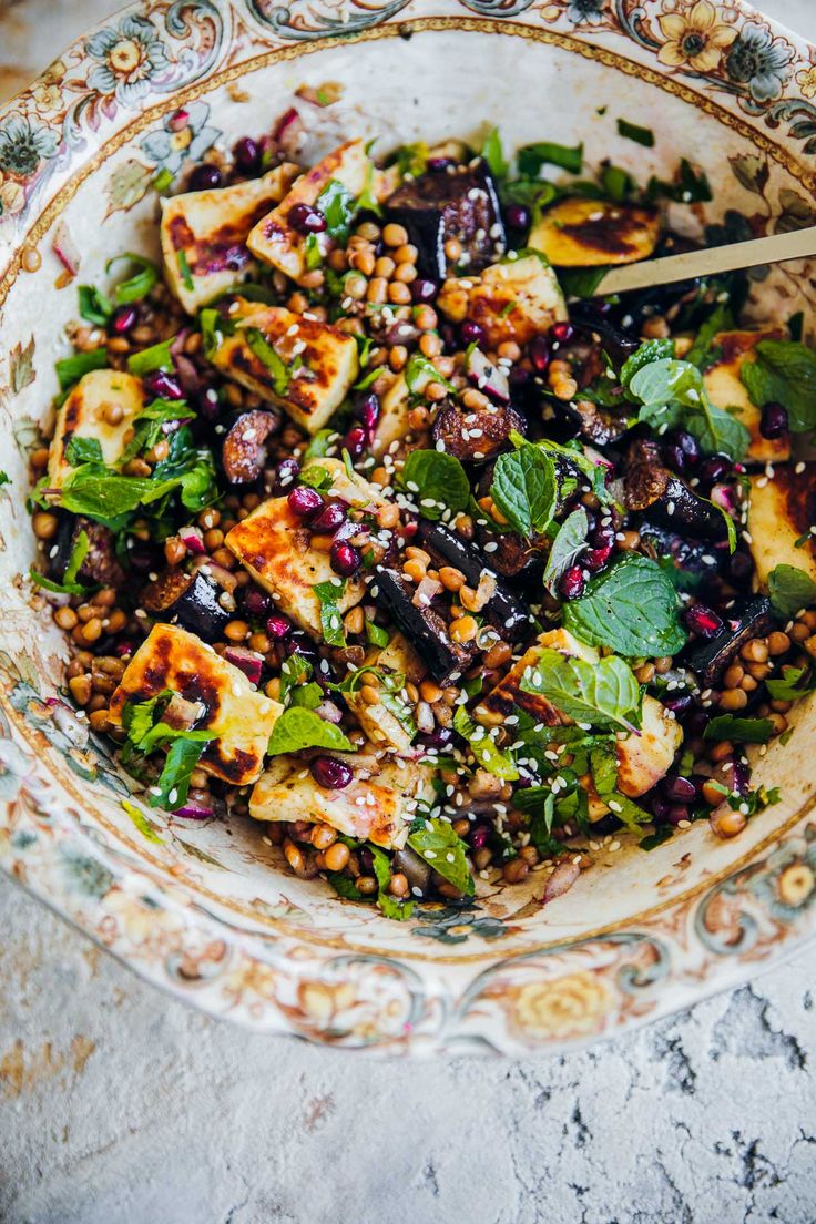 a bowl filled with vegetables and meat on top of a table next to a fork