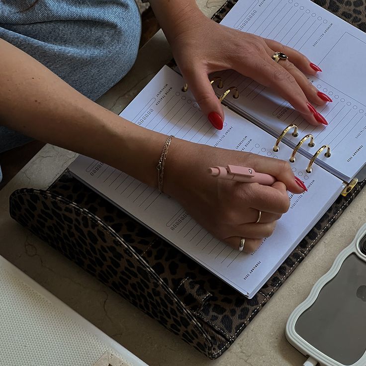 a woman's hands are on top of a binder that is holding several pairs of rings