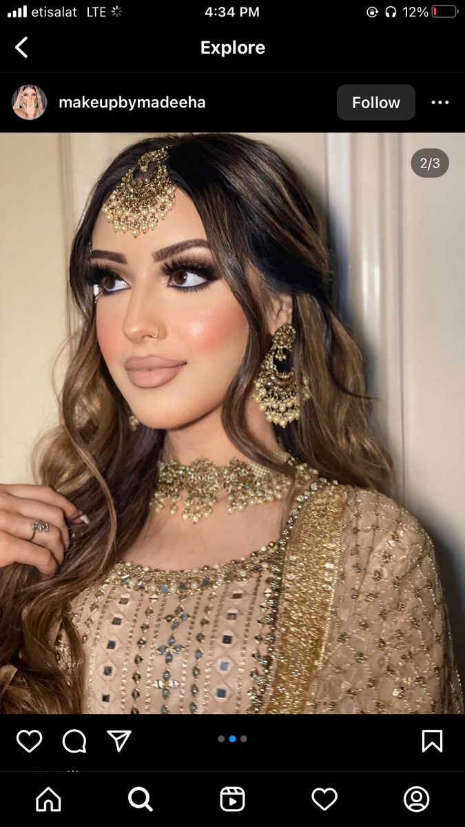 a woman with long hair wearing gold jewelry and makeup looks like she is looking at the camera