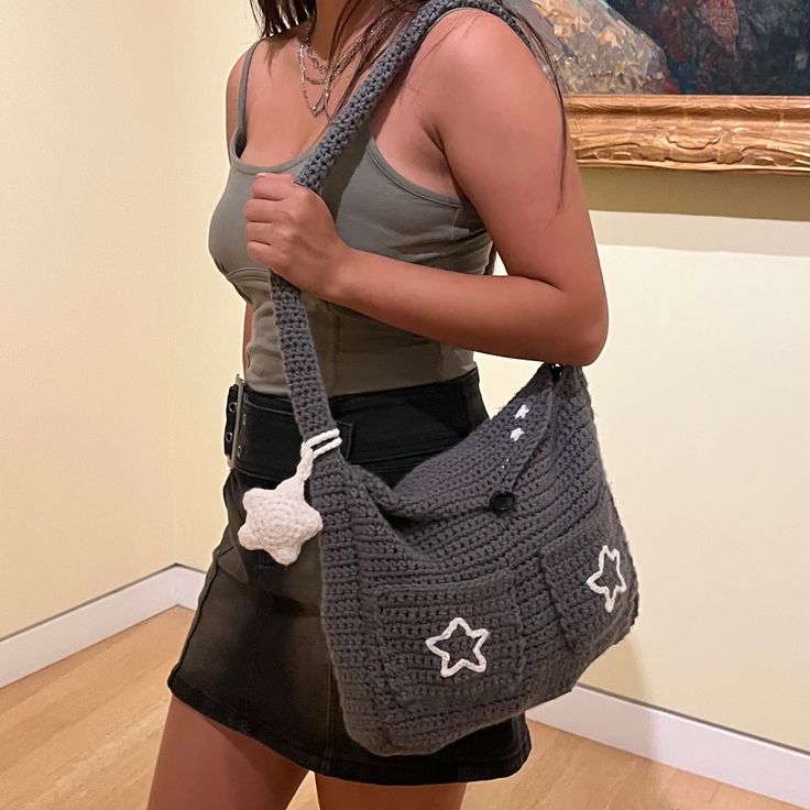 a woman holding a crocheted purse in front of a painting on the wall