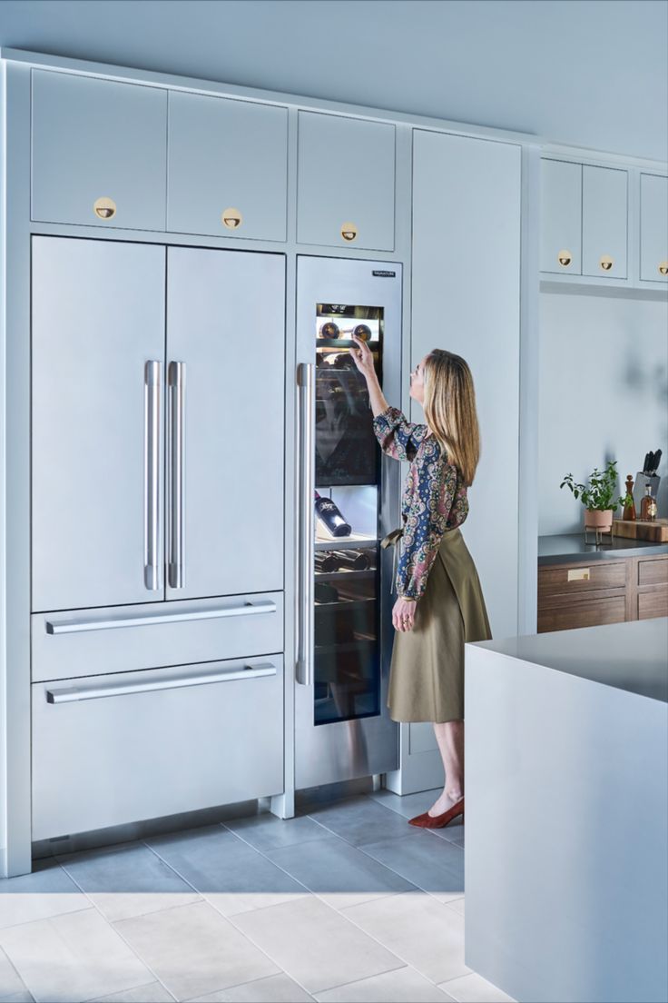 a woman is opening the refrigerator in her kitchen