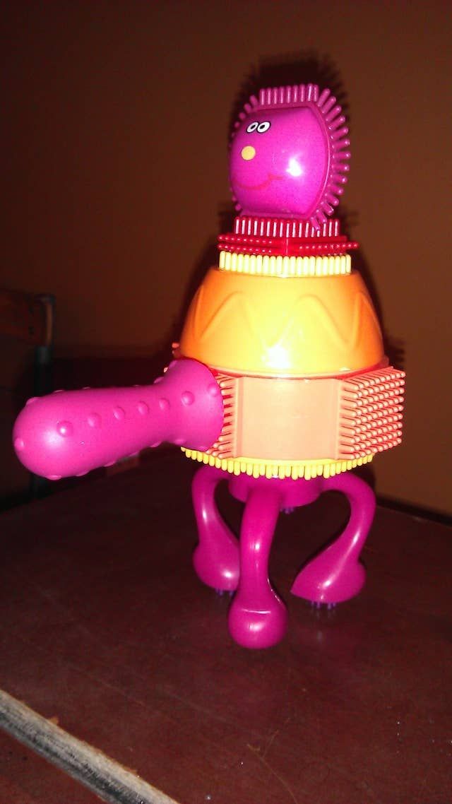 a pink and yellow toy sitting on top of a wooden table next to a wall