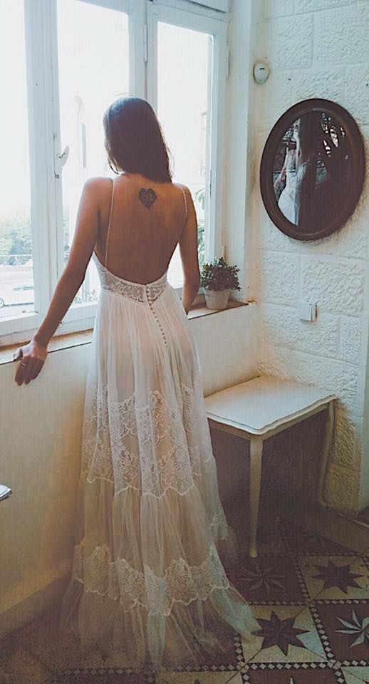 a woman standing in front of a window with her back turned to the camera and wearing a white dress