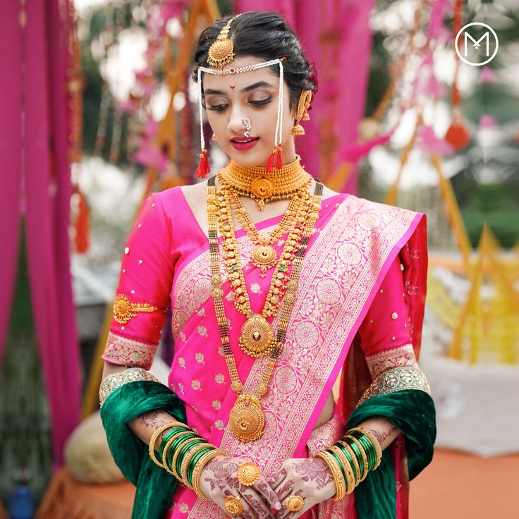 a woman in a pink and green bridal outfit with gold jewelry on her neck