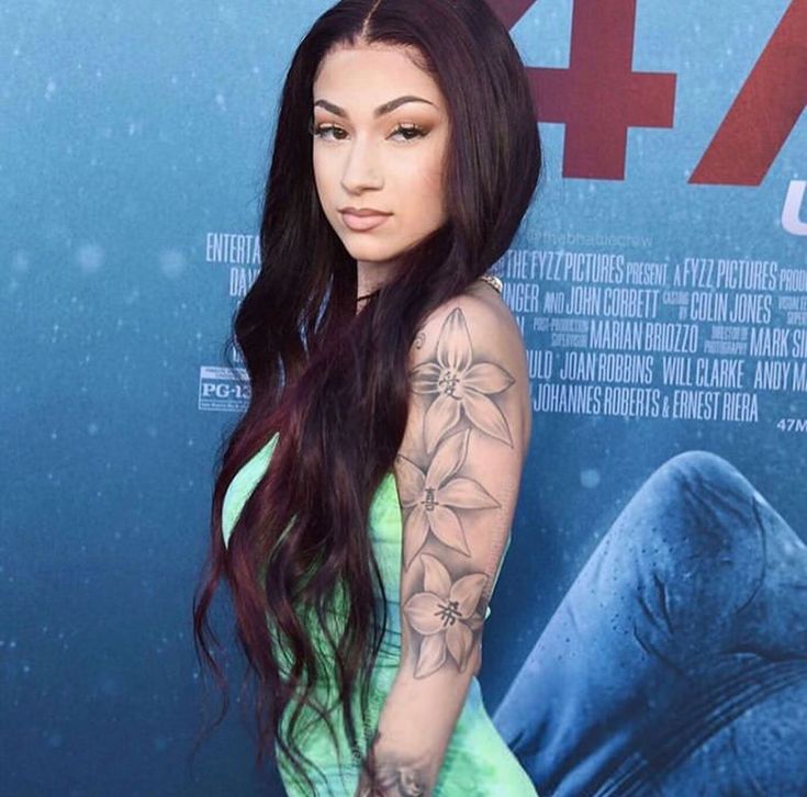 a woman with long hair and tattoos standing in front of a movie poster at an event