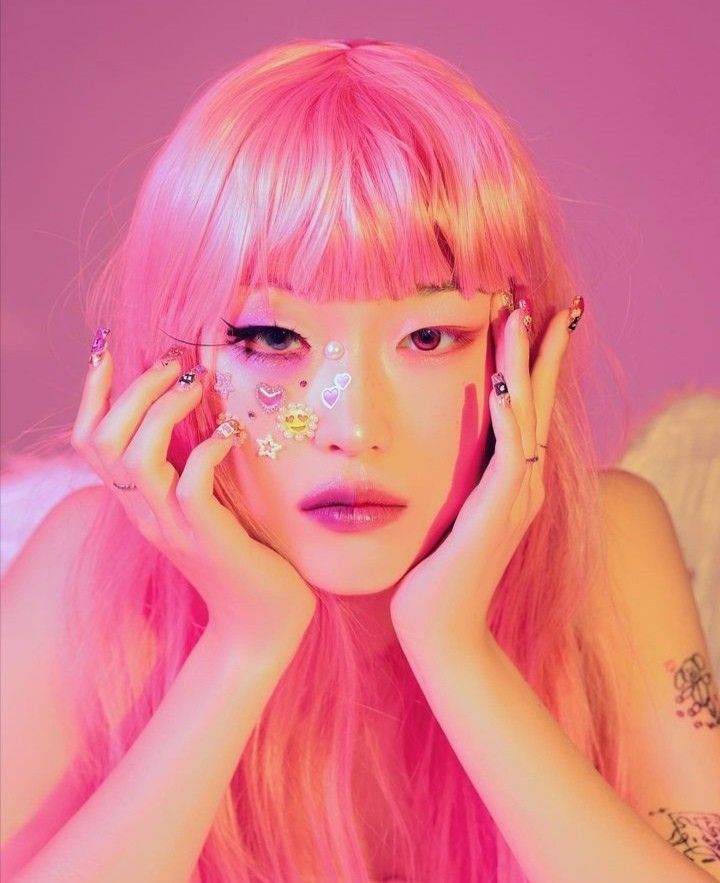 a woman with pink hair and piercings on her face is posing for the camera