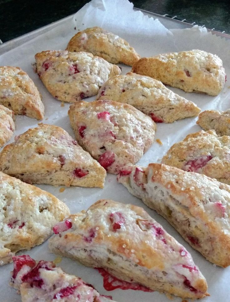 some scones that are sitting on a piece of wax paper with cranberry toppings